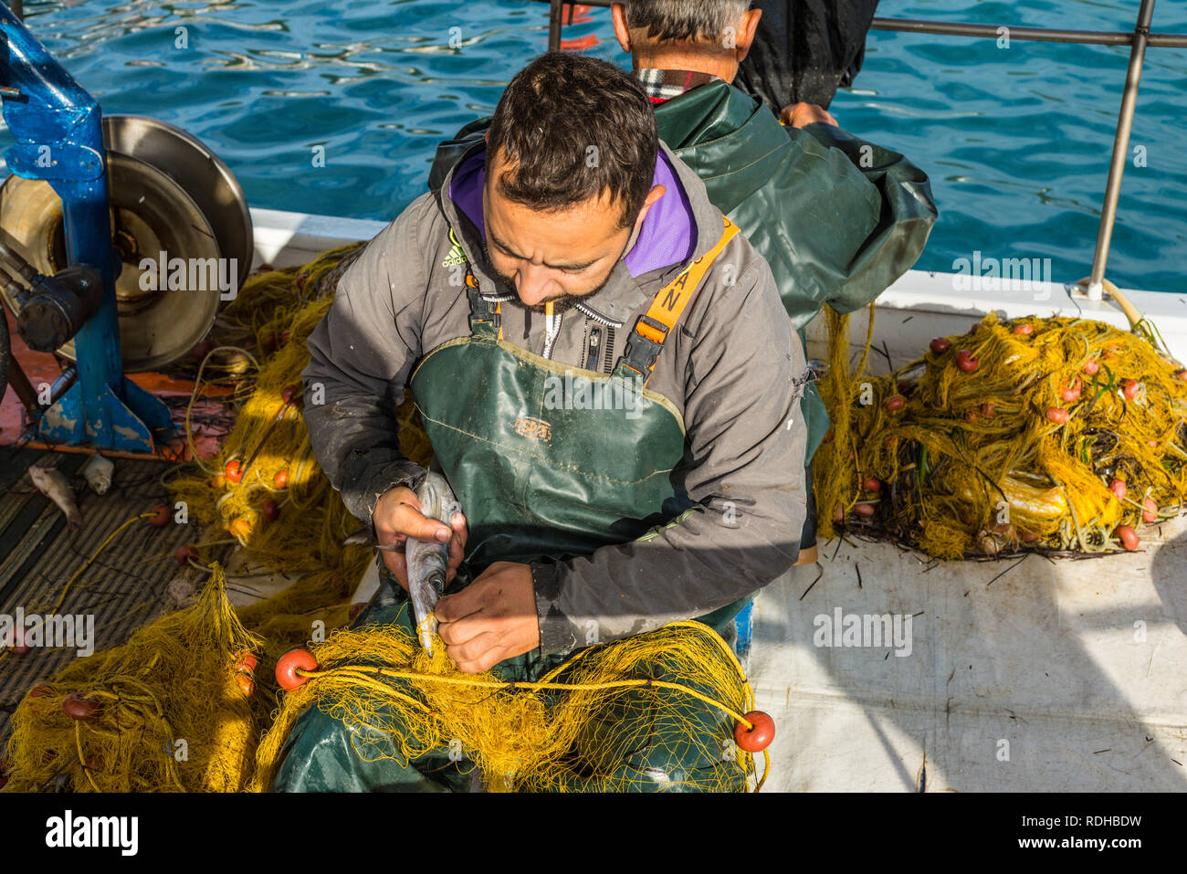 Katakolon, Grecia - 31 Ottobre 2017: i pescatori greci raccogliere il pesce nelle reti dopo la pesca nella sua barca. La pesca in legno barche tradizionali rimane Foto Stock