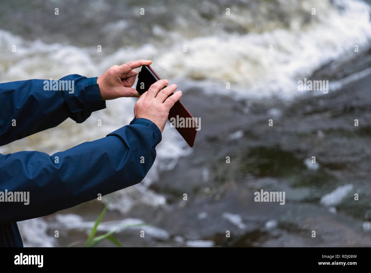 Uomo vecchio mani tenendo un telefono. Senior uomo con smart phone per scattare foto all'aperto Foto Stock