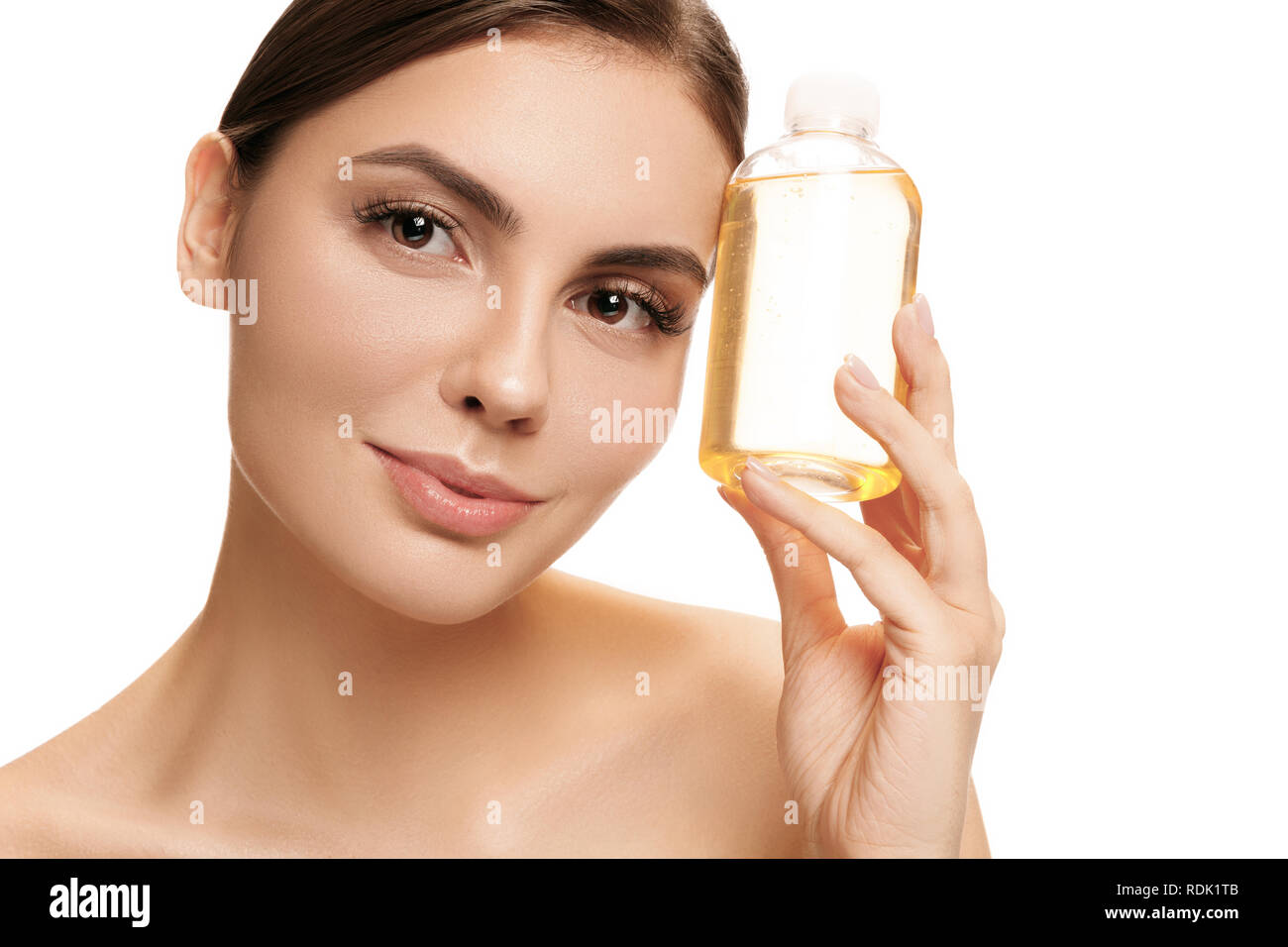 Concetto di bellezza. La Caucasian pretty woman con una pelle perfetta tenendo la bottiglia di olio in studio. La bellezza, la cura della pelle, trattamento, salute, spa, di cosmetici e di concetto di pubblicità Foto Stock