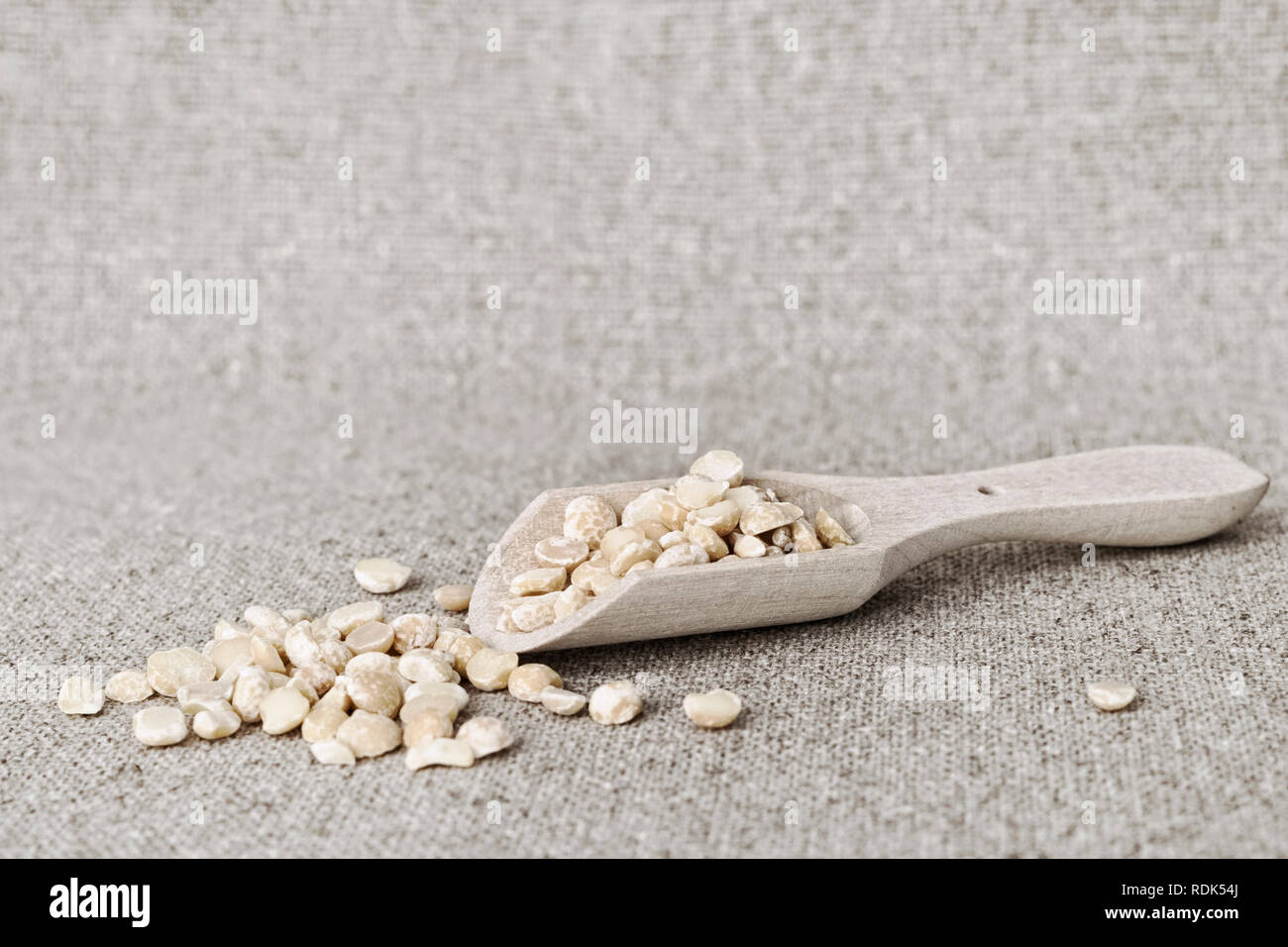 Asciugare piselli gialli in un cucchiaio di legno sul fondo della tela di vita ancora in stile rustico Foto Stock