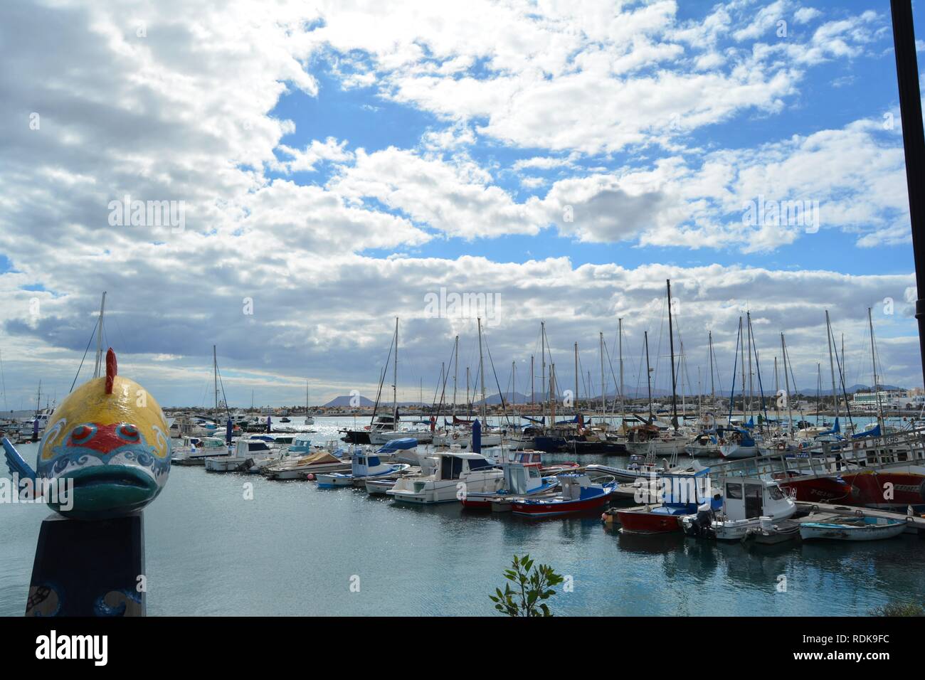 Un pesci colorati figura sul dock di Corralejo. Corralejo pier e brillante Oceano in background. Scenic sky. Fuerteventura, Spagna. Foto Stock