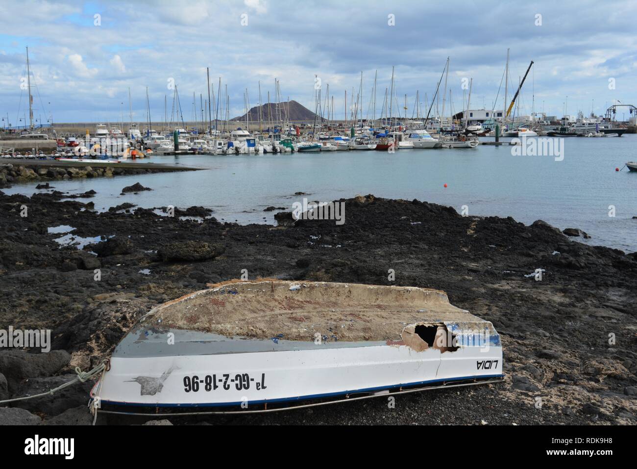 Vecchia barca abbandonata sulla costa rocciosa di Corralejo. Oceano turchese e scenic sky in background. Fuerteventura, Spagna. Foto Stock