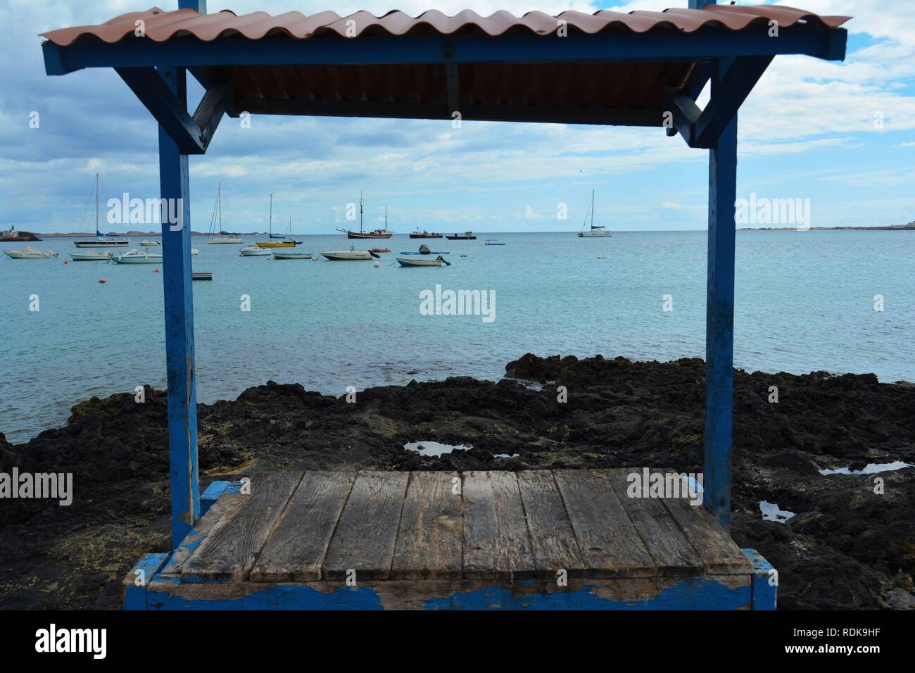 Vecchia tabella per pulire il pesce sulla costa di Corralejo, Fuerteventura, Spagna. Oceano Blu e piccole imbarcazioni in background. Foto Stock