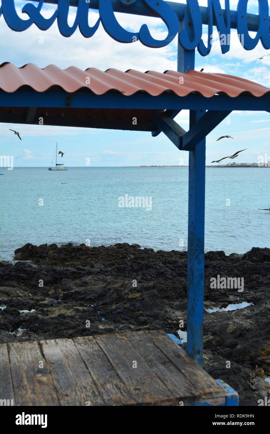 Vecchia tabella per pulire il pesce sulla costa di Corralejo, Fuerteventura, Spagna. Oceano Blu e piccole imbarcazioni in background. Foto Stock
