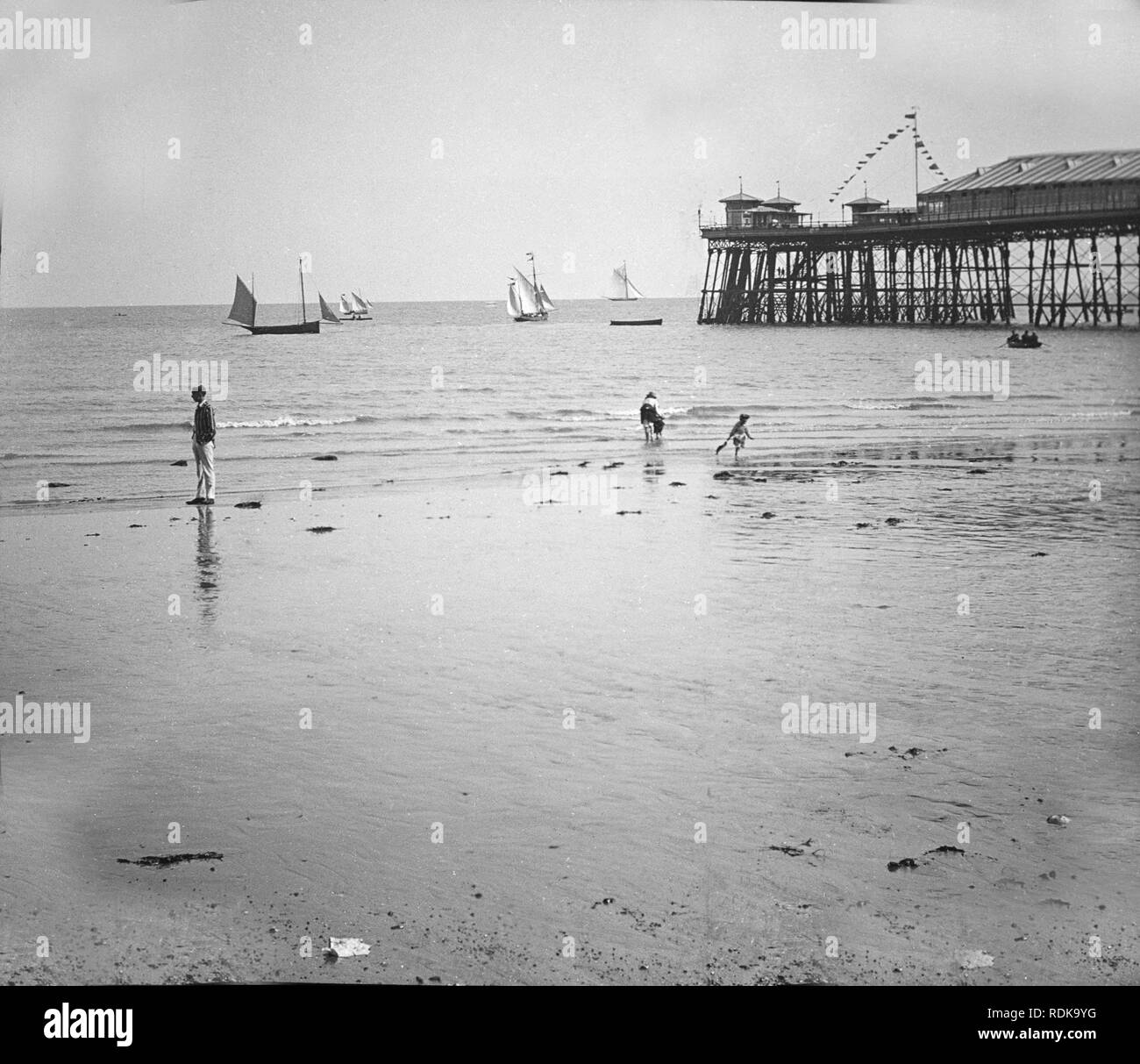 Late Victorian fotografia che mostra la spiaggia e la fine del molo di Brighton, Inghilterra. Alcune piccole imbarcazioni a vela sul mare e un paio di persone di godersi la spiaggia. Foto Stock