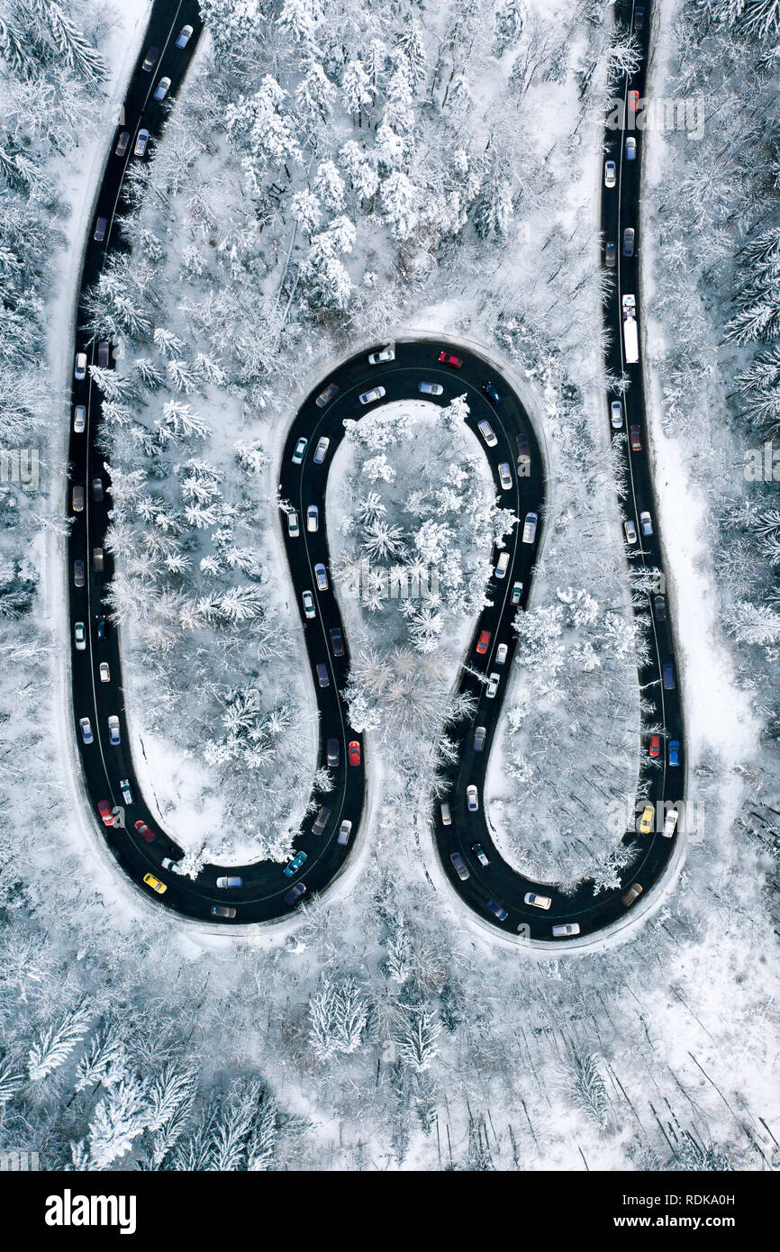 Il traffico su strada attraverso le montagne. Vacanza traffico vista aerea di un rush hour dopo una nevicata. Inverno meteo e traffico invernale co Foto Stock