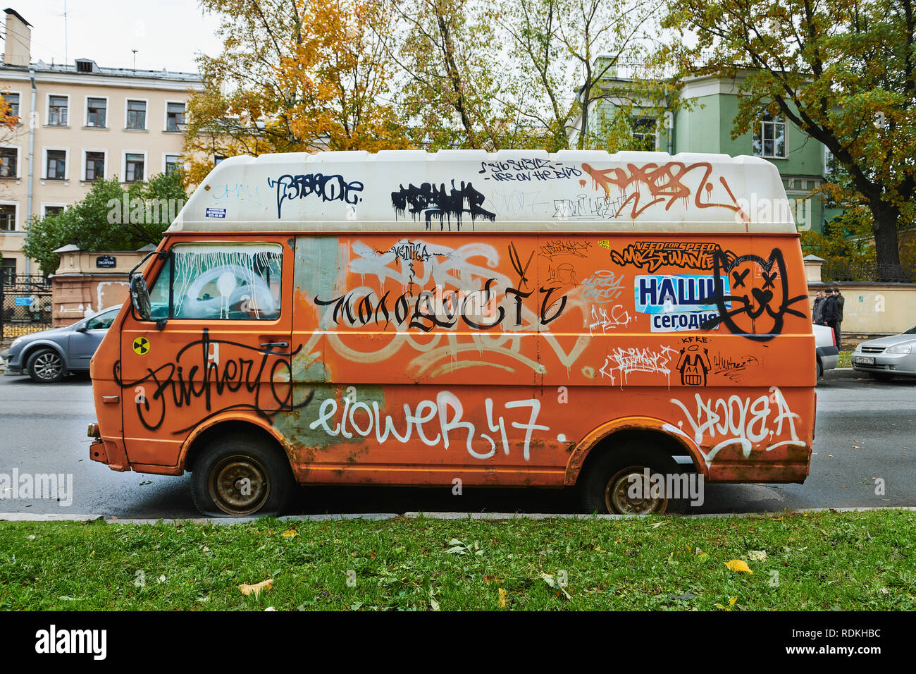Vecchio rotto orange van completamente riddled con graffiti Foto Stock