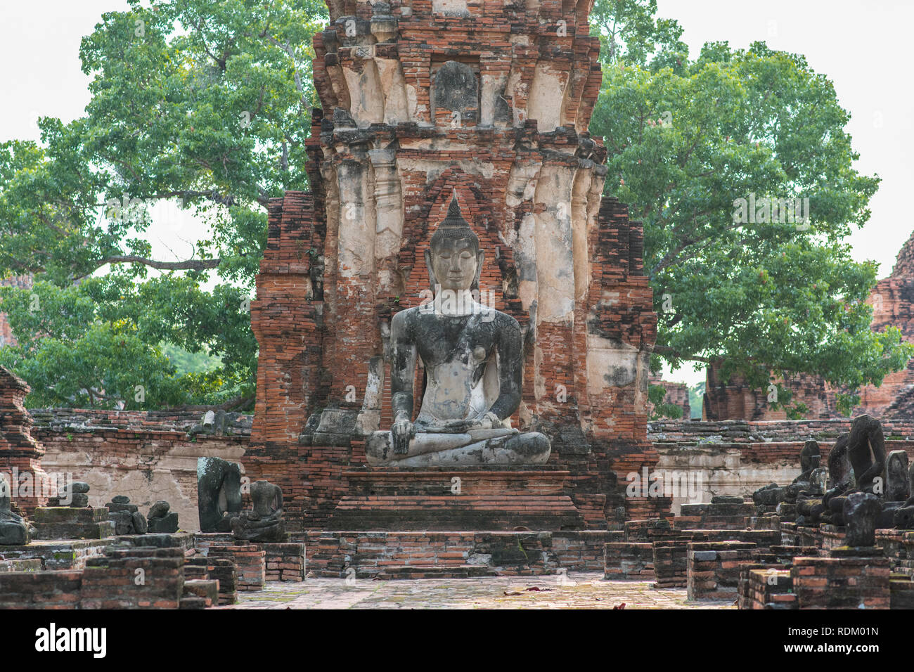 Budda seduto di Wat Phra Mahathat (Mahatat) in Ayutthaya, Thailandia. Rovine di un decorato torre in mattoni e una statua di un antico tempio buddista Foto Stock