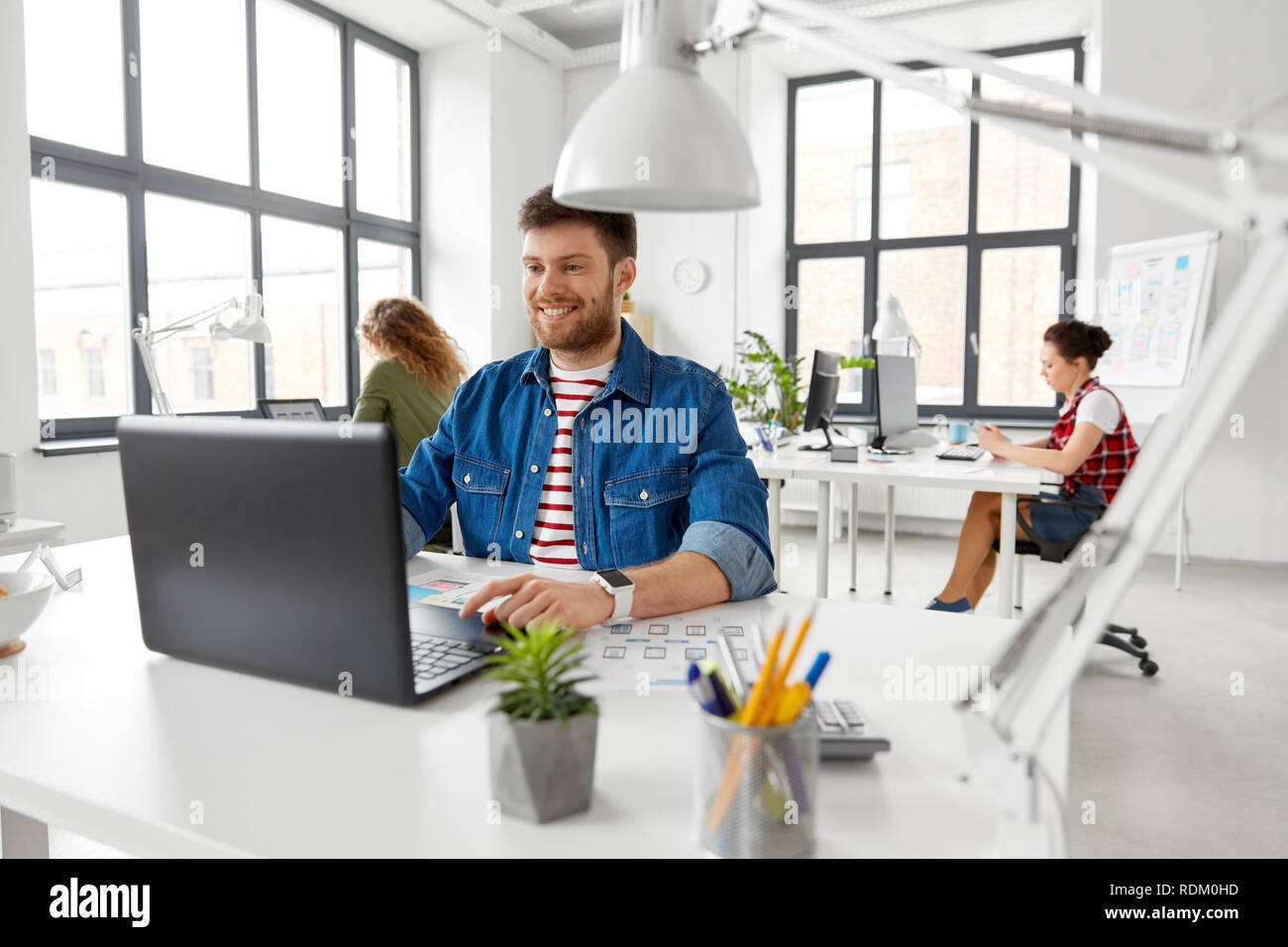 Sorridente uomo creativo con il computer portatile lavorando in ufficio Foto Stock