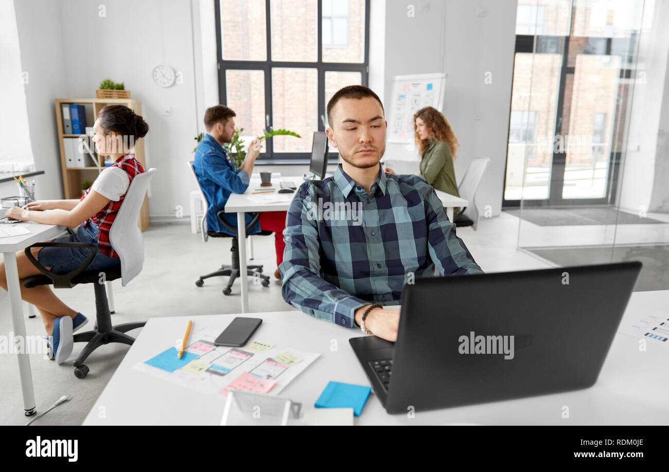 Uomo creativo con il computer portatile lavorando in ufficio Foto Stock