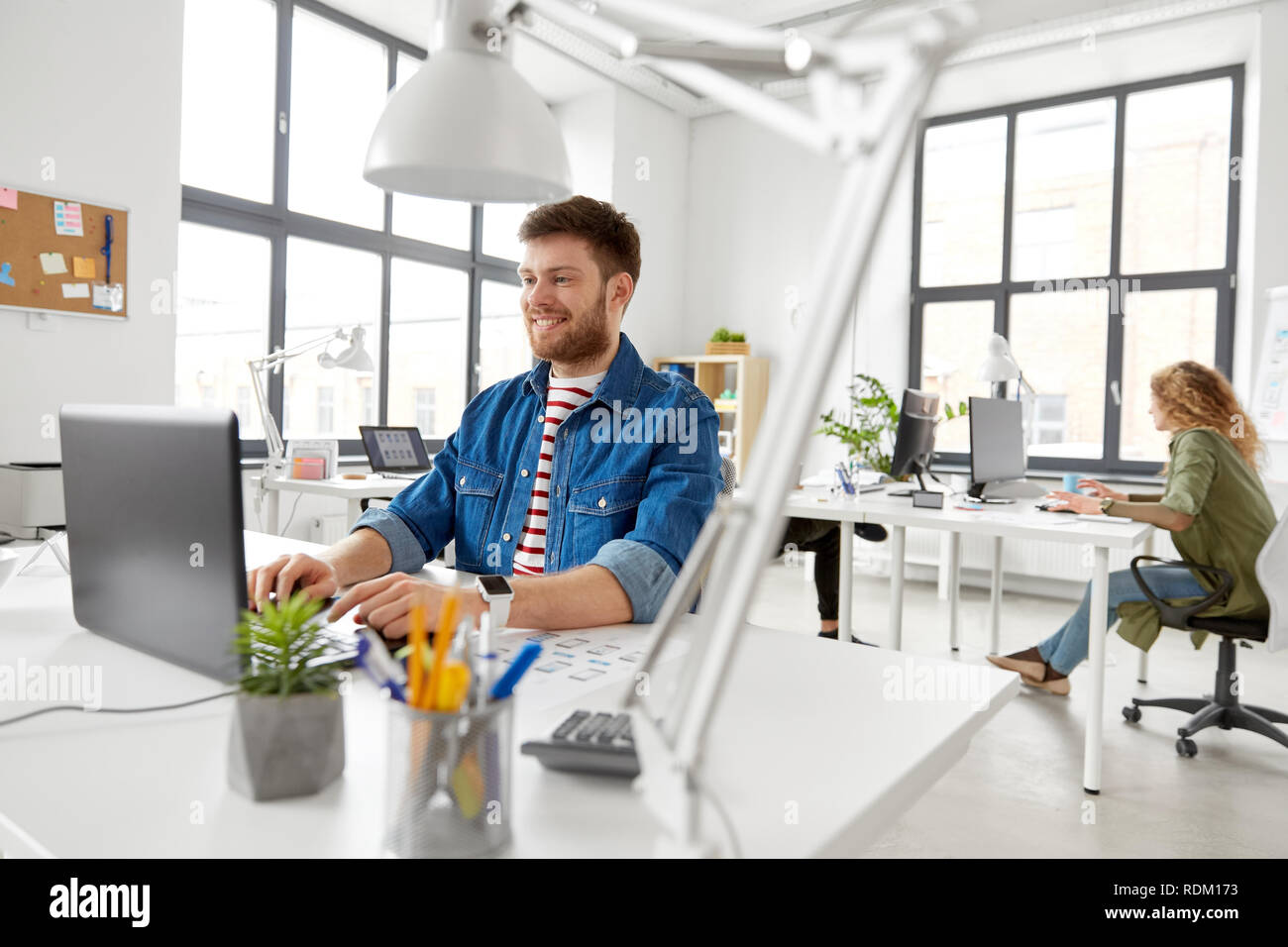 Sorridente uomo creativo con il computer portatile lavorando in ufficio Foto Stock
