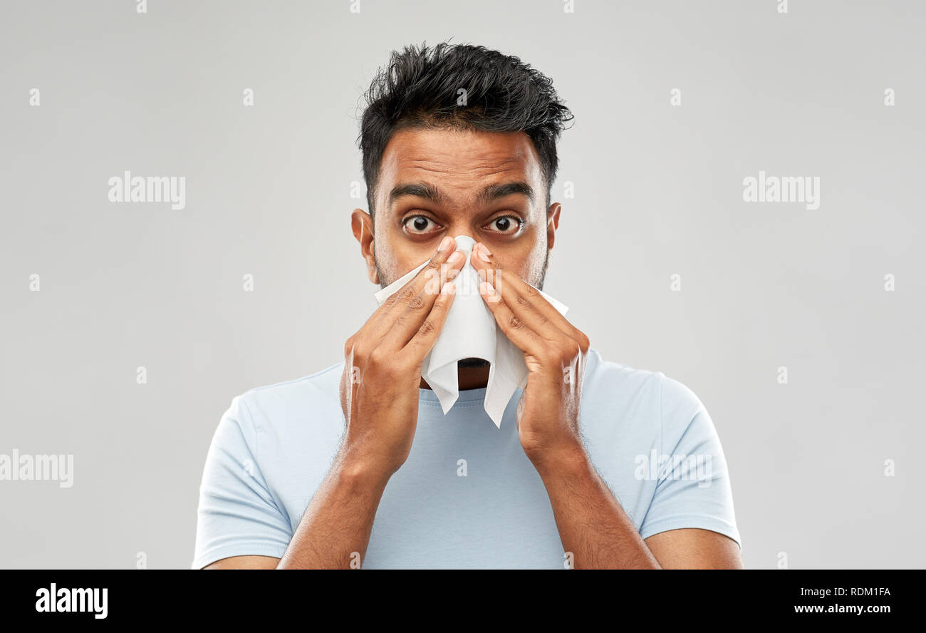 Uomo indiano con il tovagliolo di carta soffia il naso Foto Stock