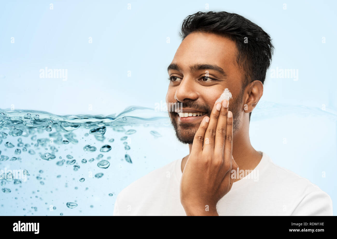 Felice l'uomo indiano l'applicazione di crema viso Foto Stock