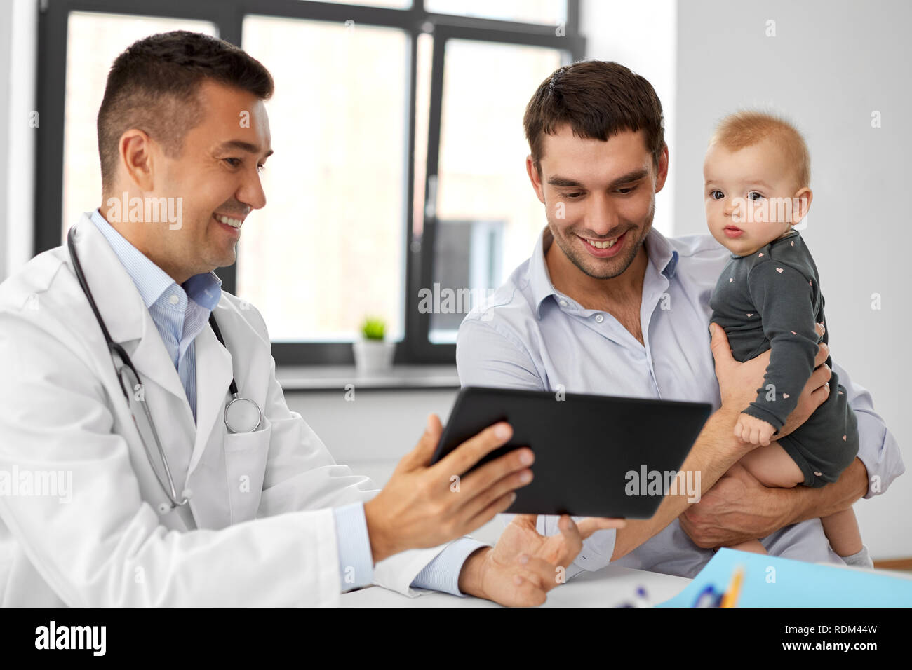 Padre con il bambino e il medico con una compressa alla clinica Foto Stock