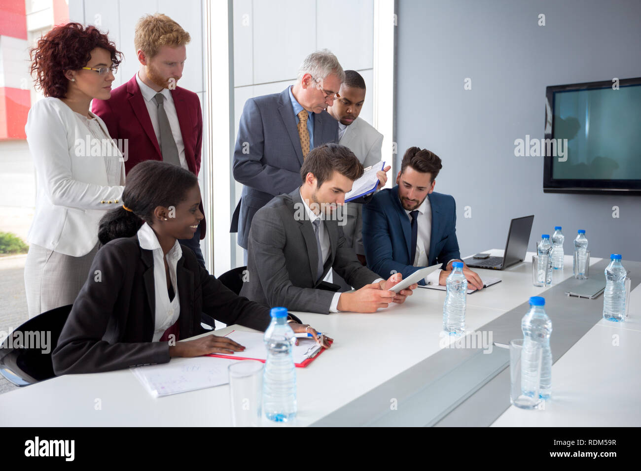 Datore di lavoro giovane seguire i dati aziendali dalla compressa in meeting aziendale Foto Stock