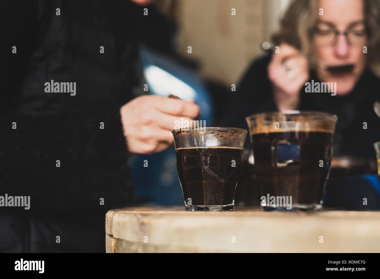 In prossimità dei due bicchieri con caffè in piedi sul tavolo di legno, persone in background. Foto Stock