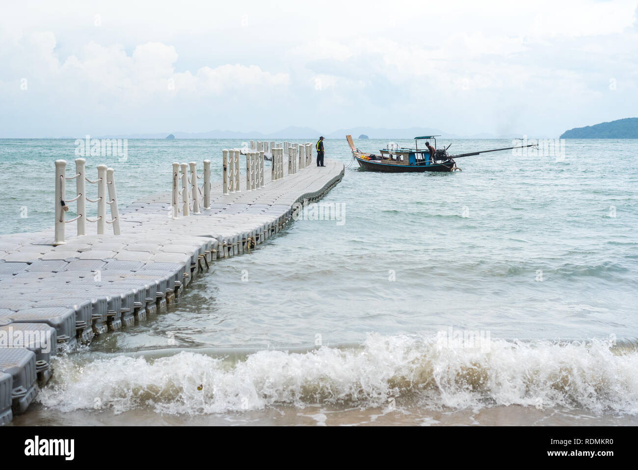 Plastica molo pontone galleggiante nel mare con un Thai imbarcazione attraccata alla sua estremità. Bassa stagione (luglio) al Pai Plong Spiaggia Ao Nang, Krabi, Thailandia. Foto Stock