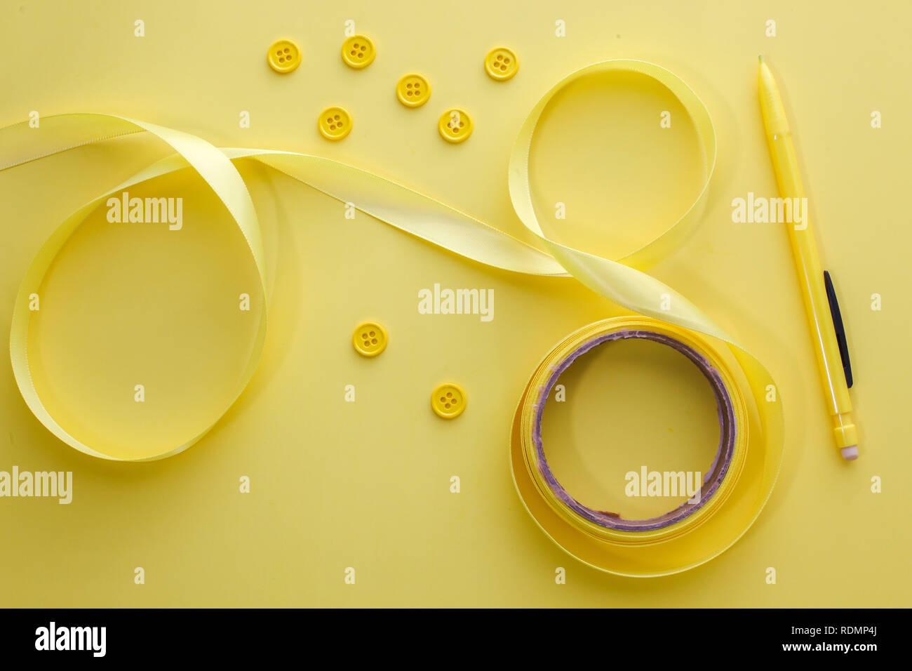 I pulsanti di colore giallo, giallo di prua e matita gialla su sfondo giallo table top Foto Stock