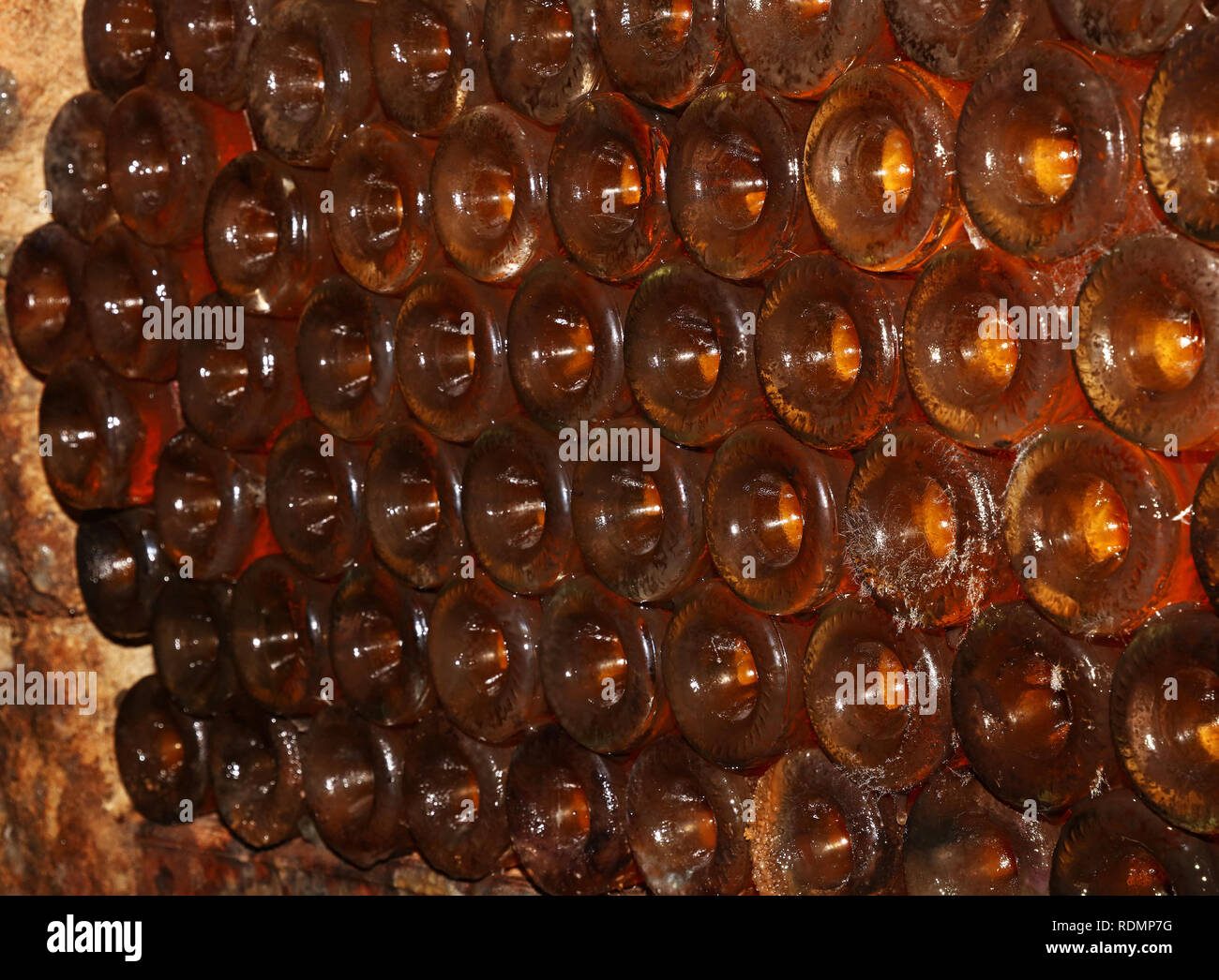 Close up righe retroilluminato di vino bianco bottiglie in vetro impilati l affinamento in cantina Foto Stock