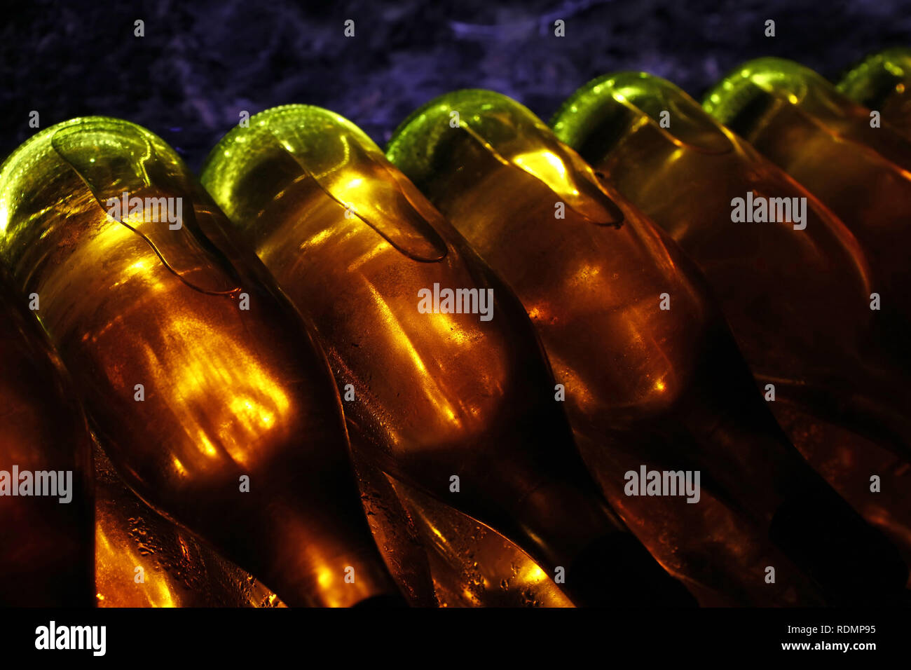 Close up righe retroilluminato di vino bianco bottiglie in vetro impilati l affinamento in cantina Foto Stock