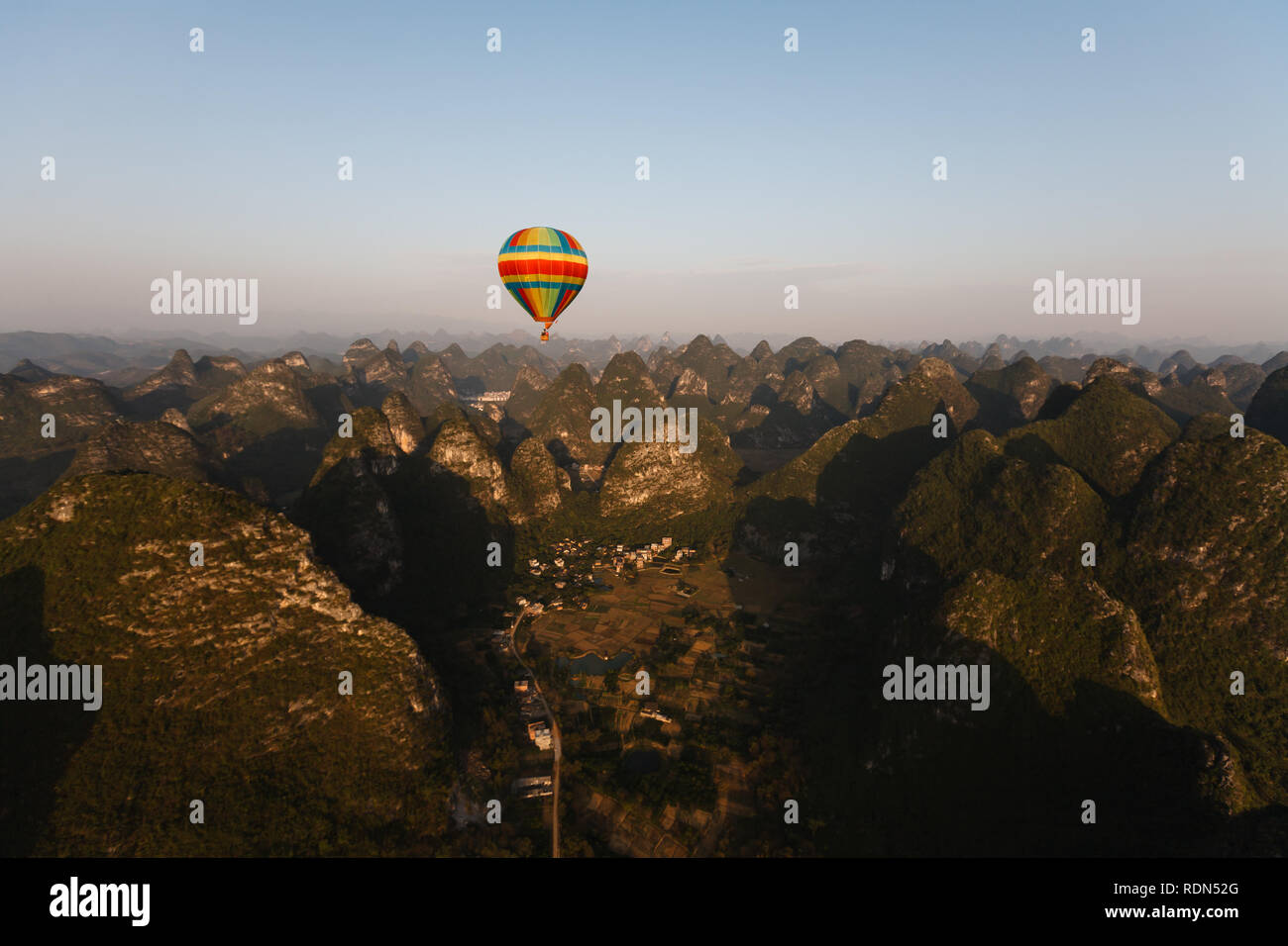 Vista aerea della montagne carsiche, campi di riso e la piccola cittadina nella valle lungo il fiume Pearl in Cina da una mongolfiera Foto Stock