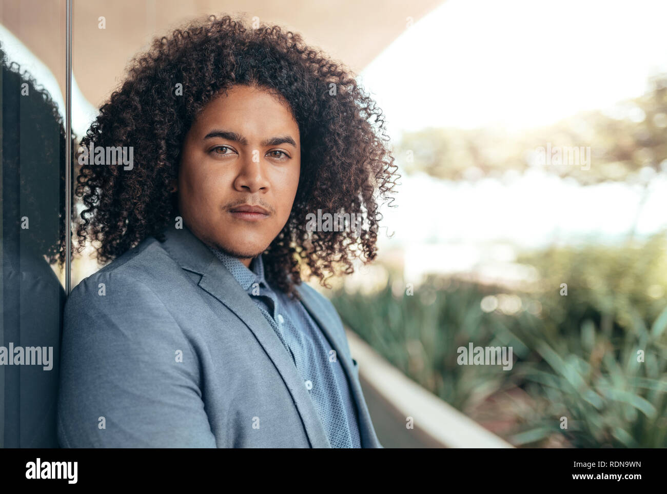 Giovani razza mista ragazzo con ricci afro guardando nella telecamera Foto Stock