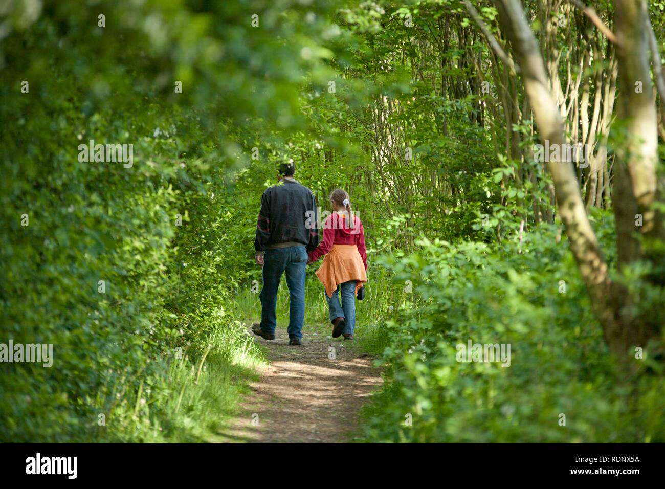 Uomo che cammina con una bambina nel bosco, poste scena Foto Stock