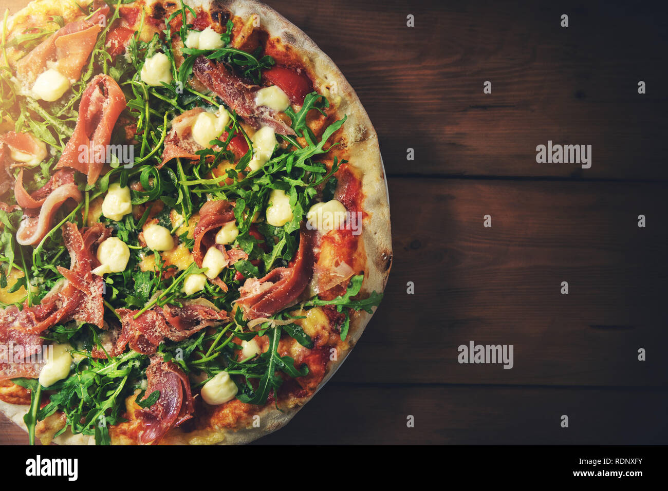 Il prosciutto rucola pizza sul legno marrone background. vista dall'alto uno spazio di copia Foto Stock