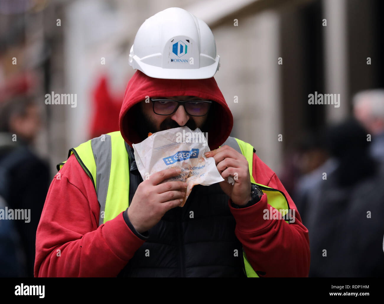 Costruttori di mangiare cibo Greggs camminando lungo Foto Stock