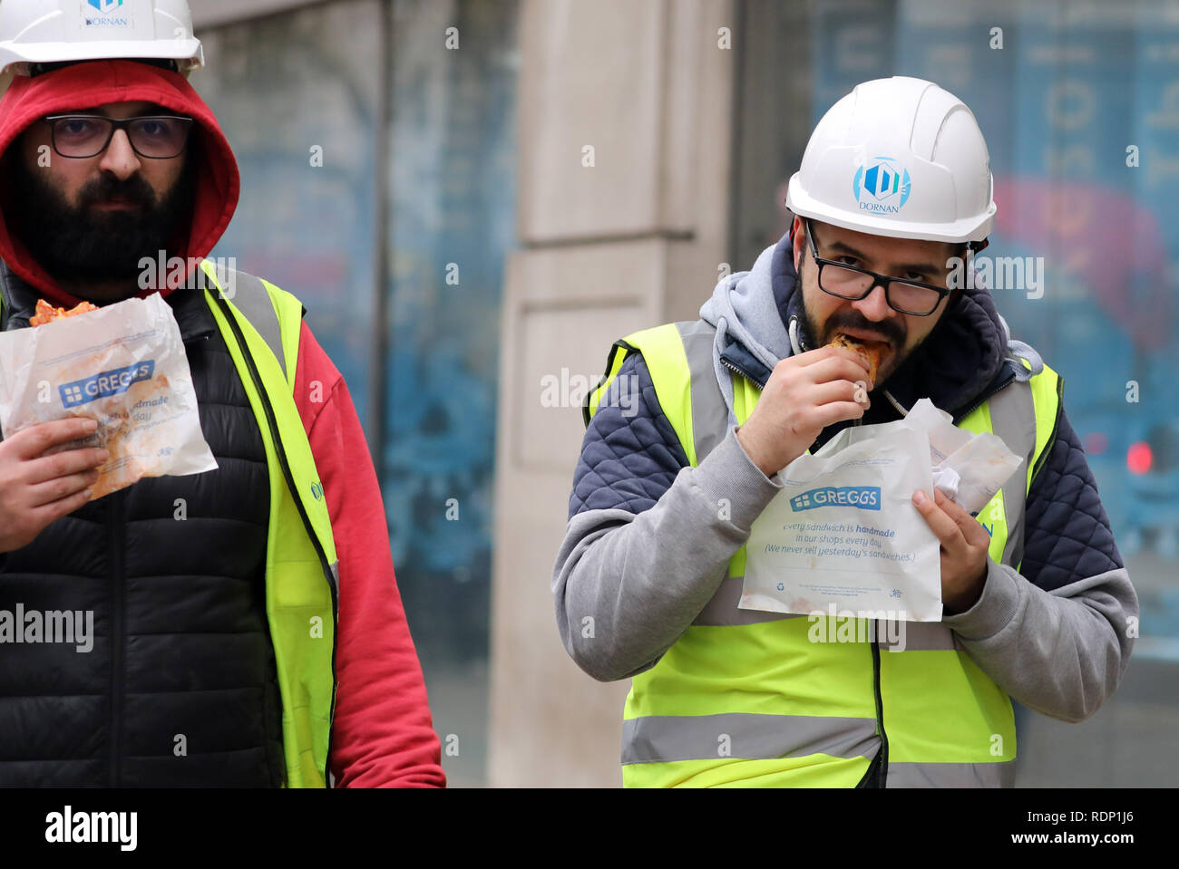 Costruttori di mangiare cibo Greggs camminando lungo Foto Stock