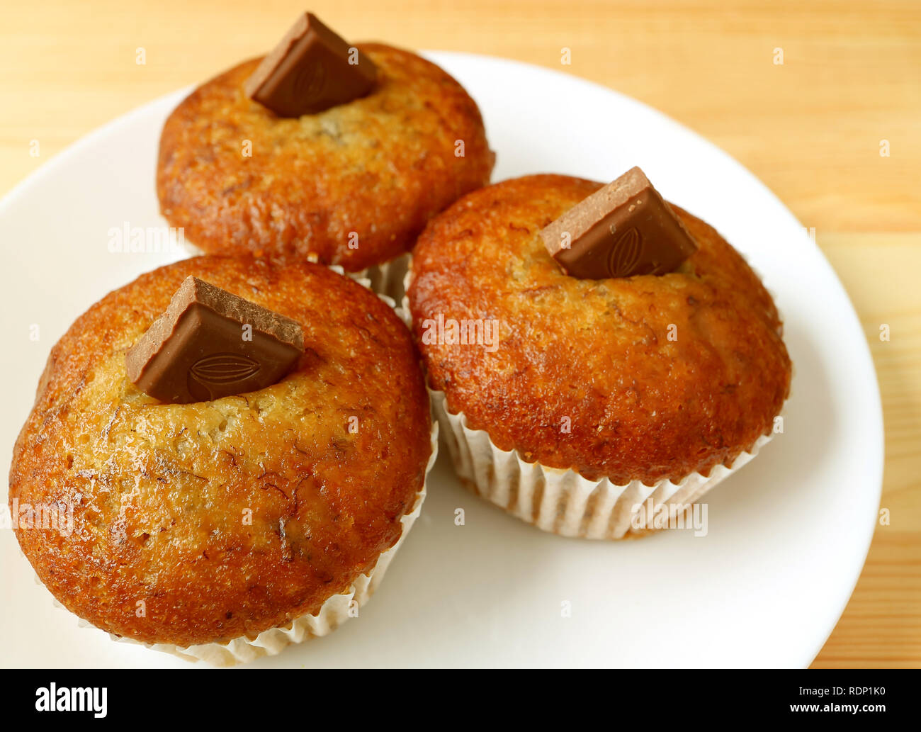 Una piastra di muffin alla banana con cioccolato al latte pezzetti servita su un tavolo di legno Foto Stock