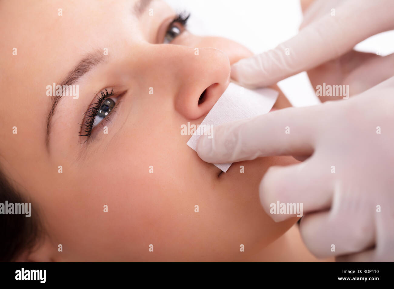 Close-up del terapeuta di ceratura di mano della donna del labbro superiore nella Spa Foto Stock