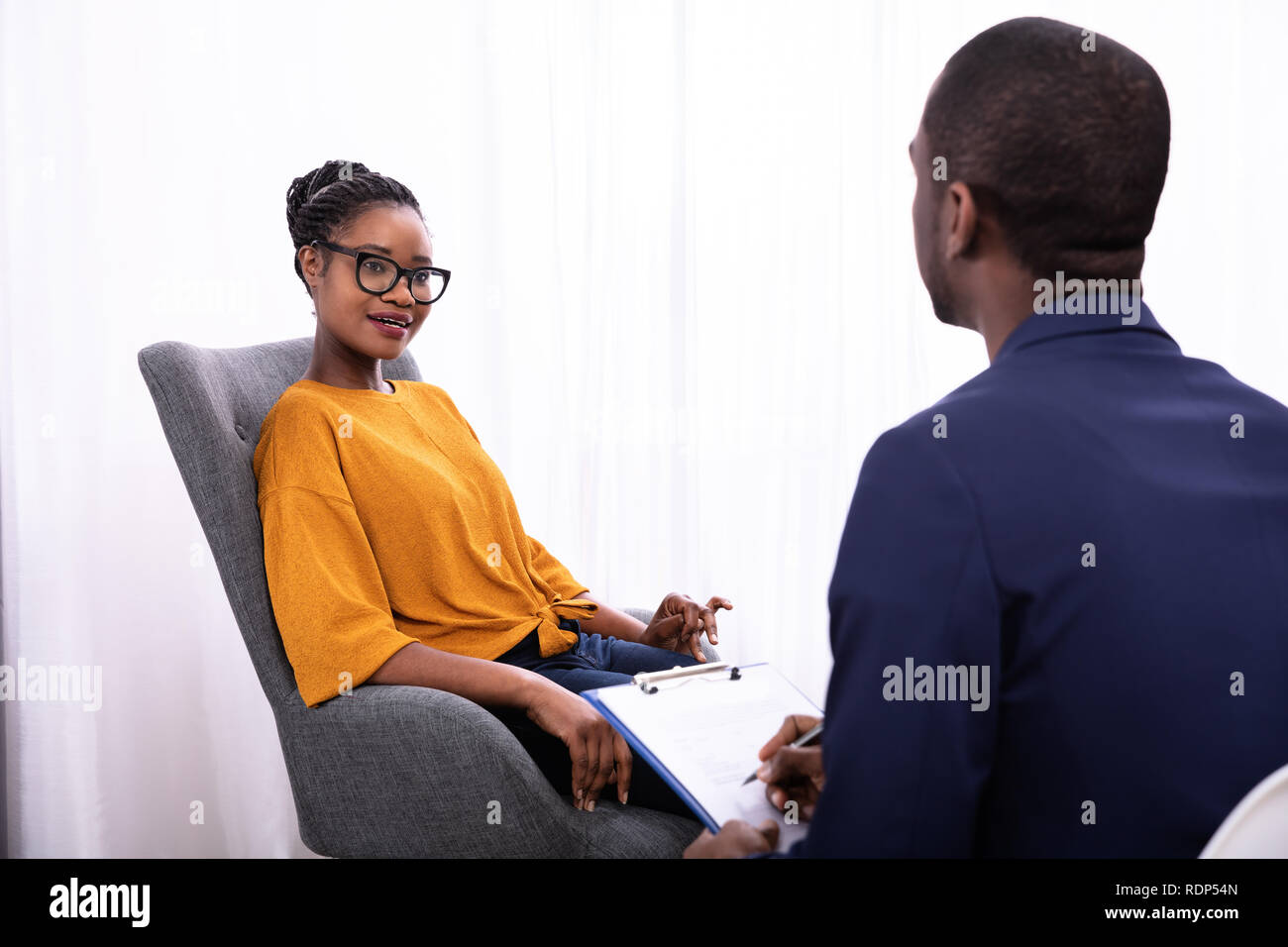 Giovane donna africana seduta vicino psicologo con appunti per trattare la depressione Foto Stock