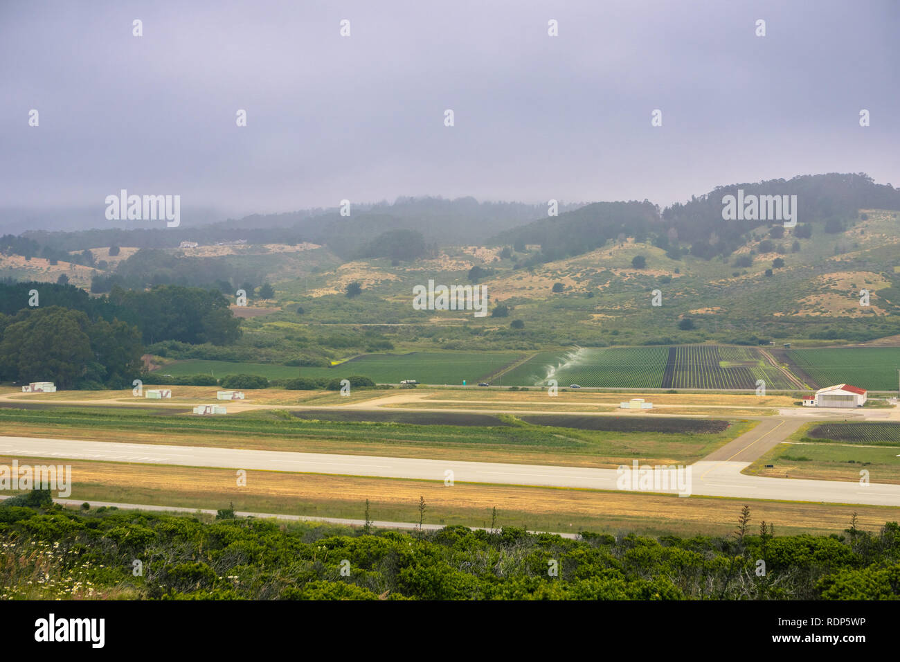 Vista aerea di campi agricoli, locale aeroporto pista e colline coperte di nebbia, Moss Beach, California Foto Stock