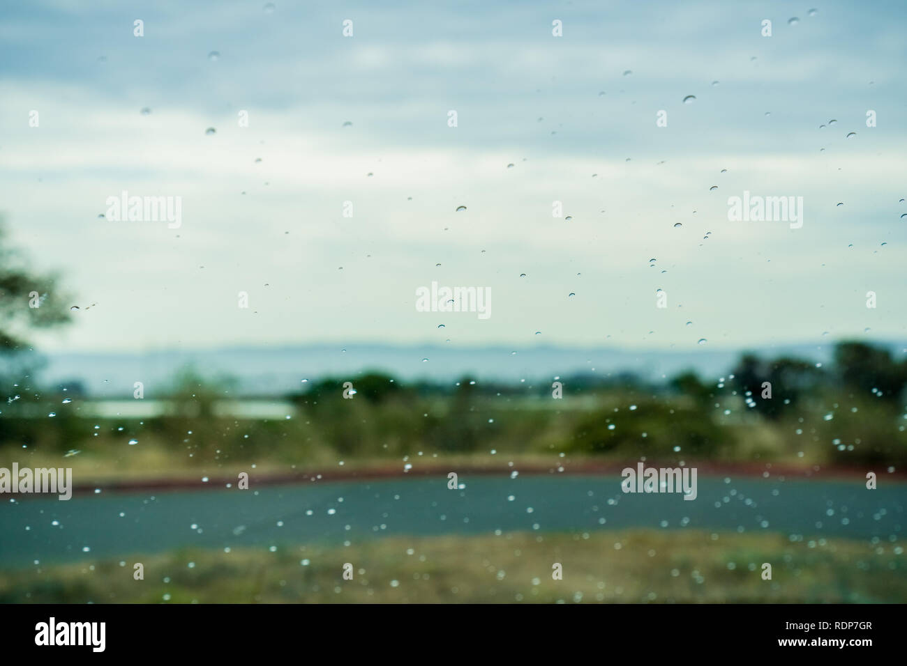 Gocce di pioggia sulla finestra; paesaggio sfocata in background Foto Stock