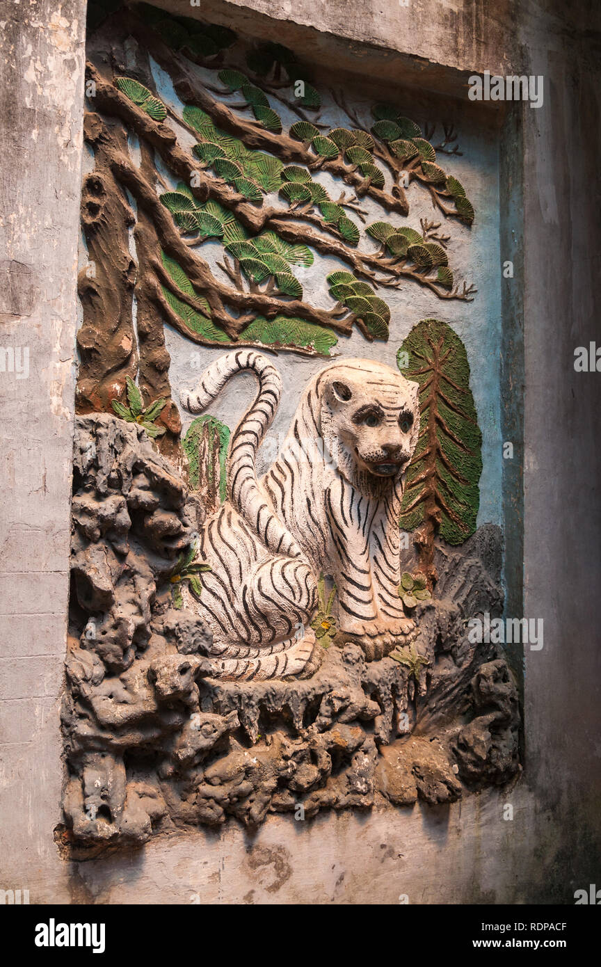 Pietra di sfiato artwork simbologia animale di una tigre sotto un albero sulla parete del taoista Thánh Quán tempio ( Đền Quán Thánh ), Hanoi, Vietnam Foto Stock