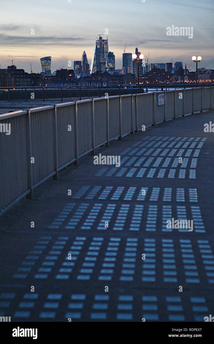 Vista su un marciapiede modellato verso la città di Londra da Canary Wharf al crepuscolo Foto Stock