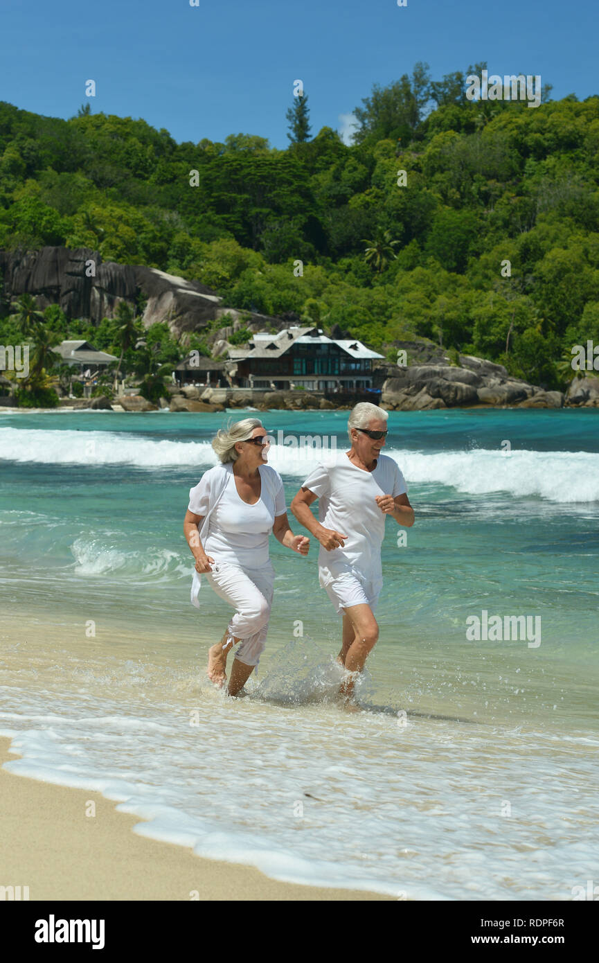 Ritratto di felice coppia di anziani in esecuzione sulla spiaggia tropicale Foto Stock