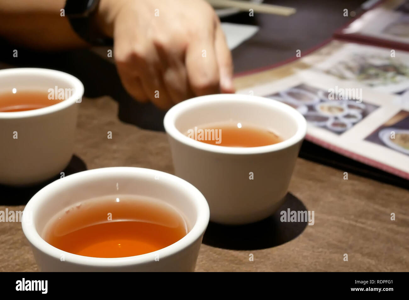 Close up della donna che guarda al menu e tè caldo sulla tabella all'interno del ristorante cinese Foto Stock