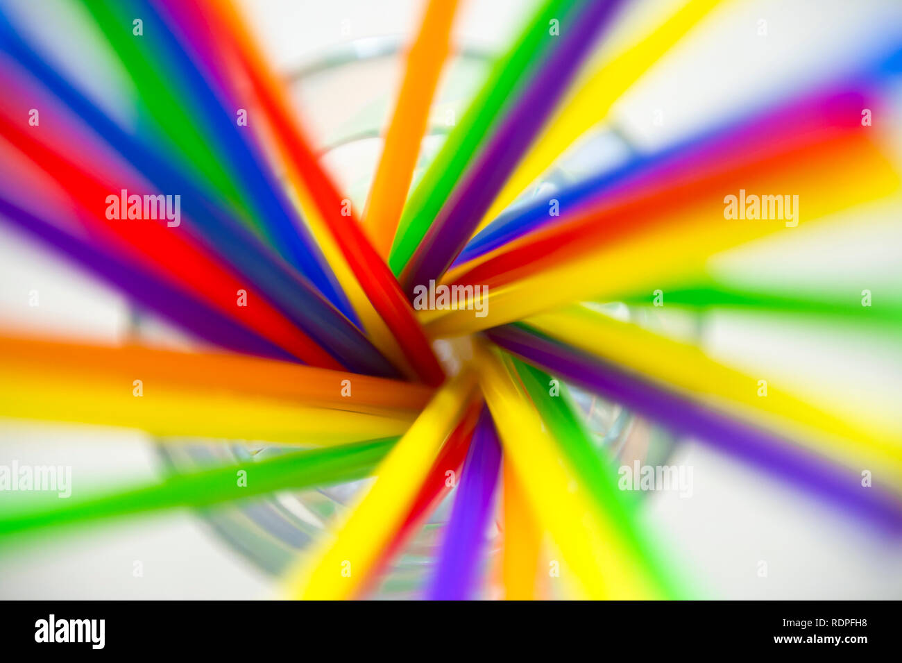 Bicchiere pieno di Colorati luminosamente cannucce di plastica volteggiando in una sfocatura del movimento Foto Stock