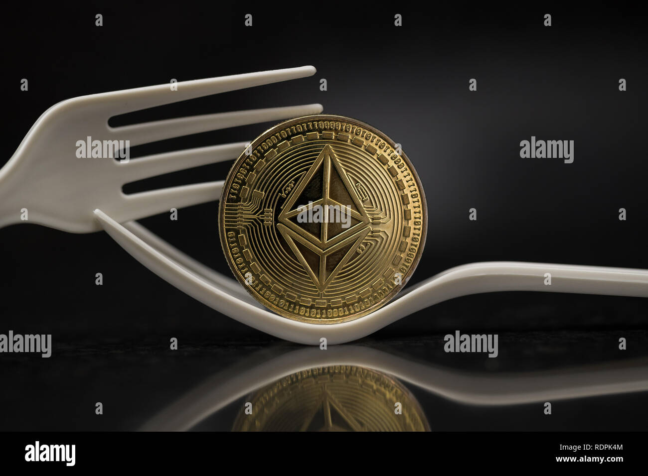 Ethereum Classic cryptocurrency moneta fisica posto sulla forcella di plastica in sfondo nero Foto Stock