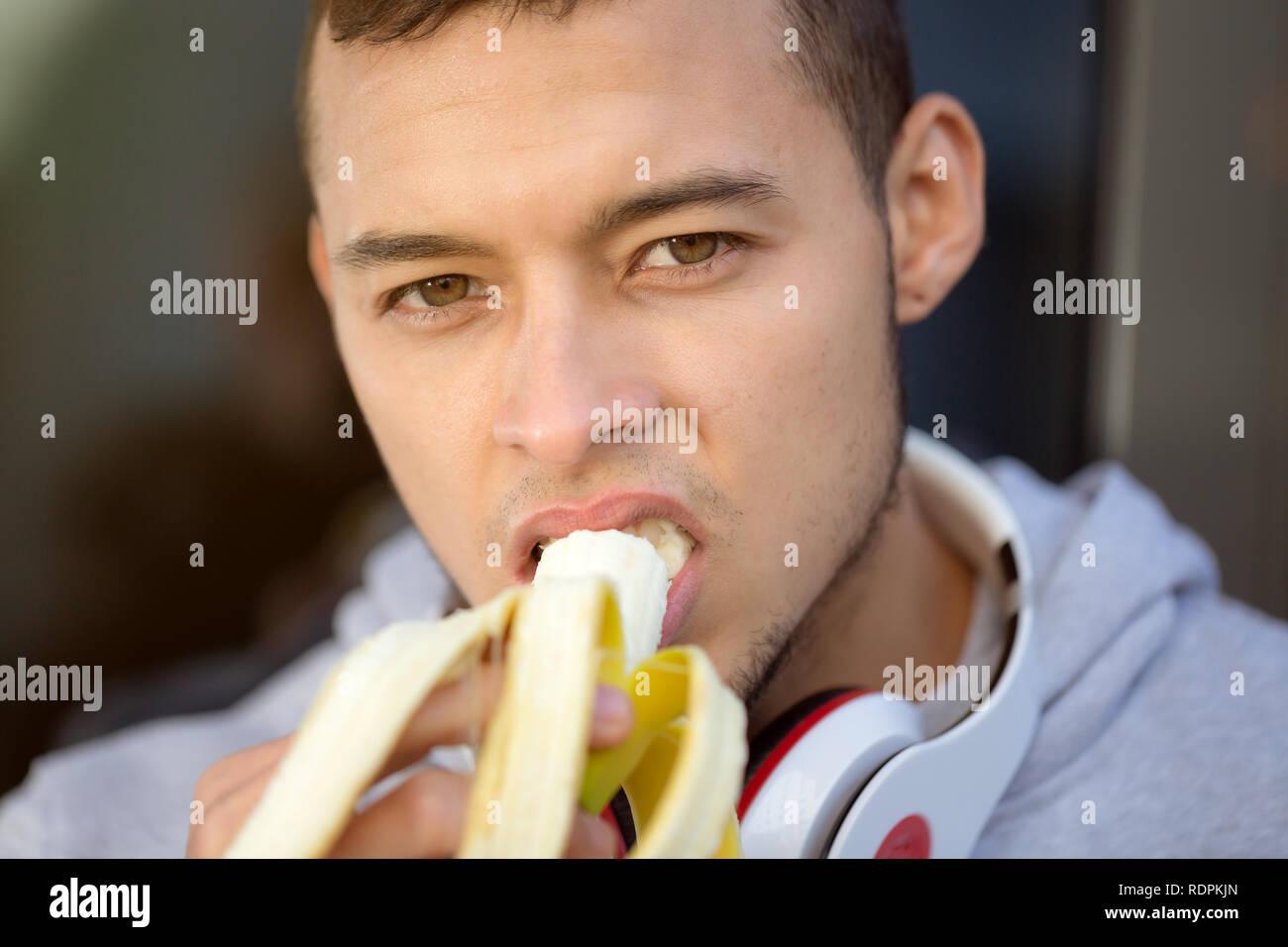 Giovane uomo latino mangiare frutta banana runner in inverno in esecuzione formazione sportiva outdoor fitness Foto Stock