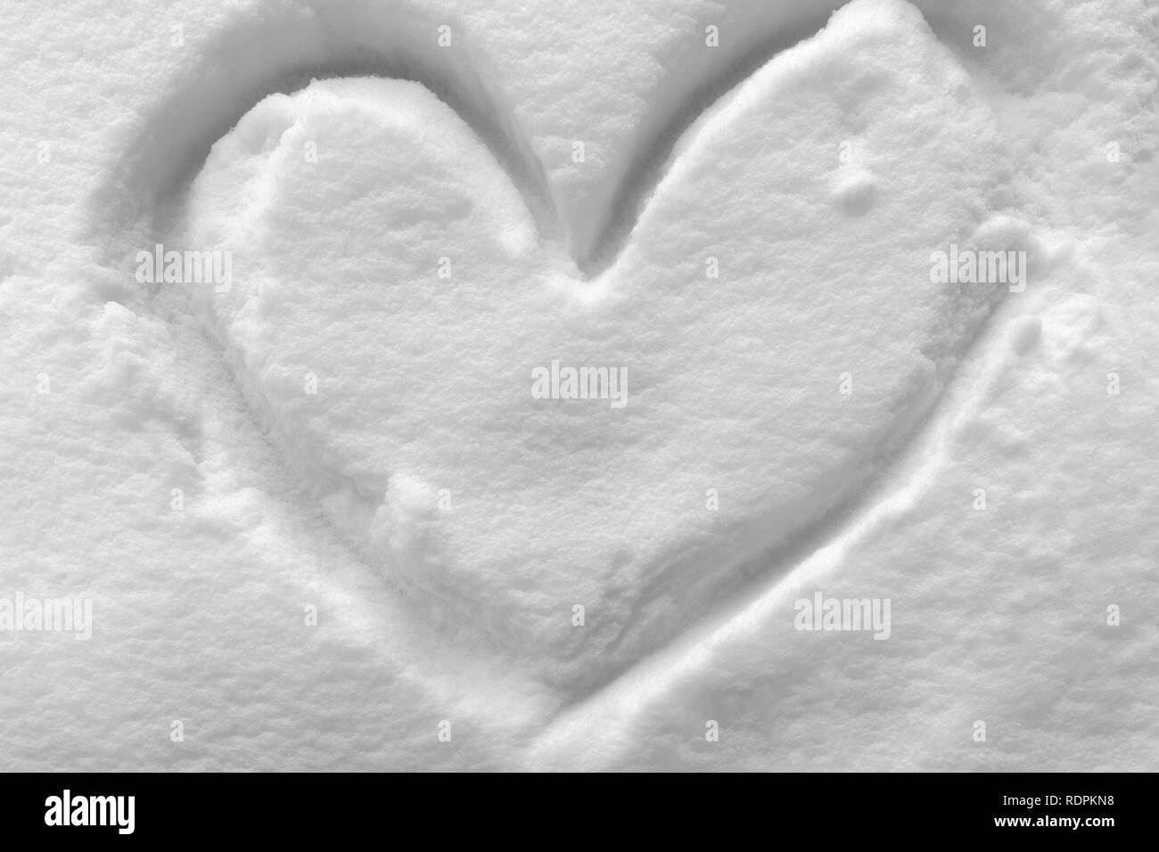 Forma di cuore simbolo disegnato sul bianco della neve in inverno freddo Foto Stock