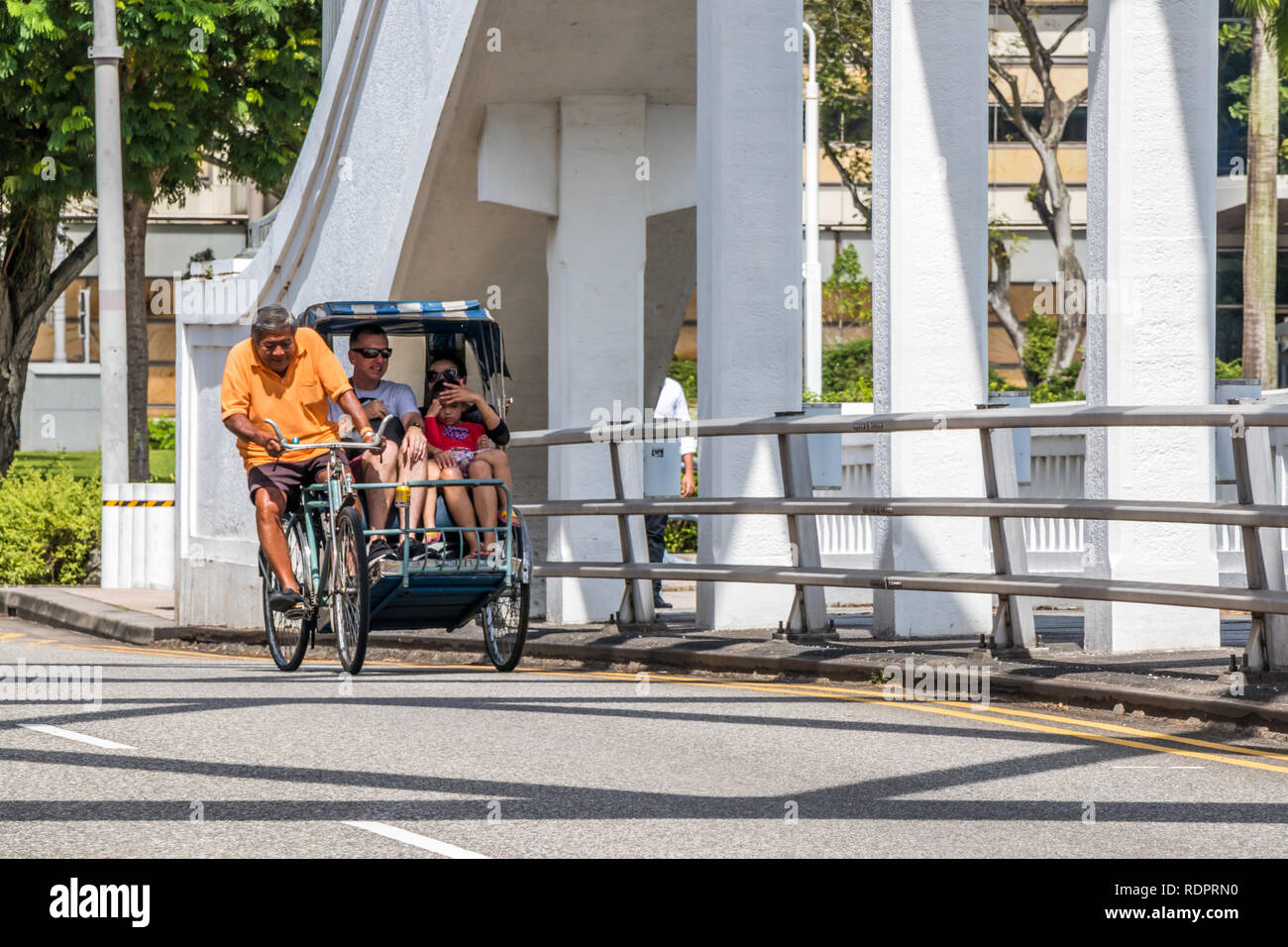 Singapore - 26 dicembre 2018: un risciò ciclo con passeggeri fa il suo modo al di sopra di Elgin Bridge. Cyclo sono ancora utilizzati dai turisti. Foto Stock
