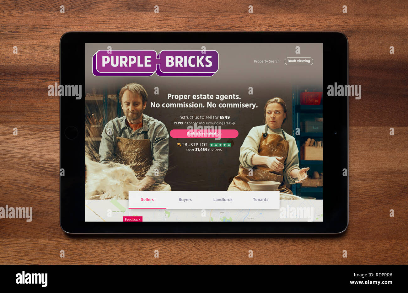 Il sito web di mattoni di colore viola è visto su un tablet iPad, il quale è appoggiato su un tavolo di legno (solo uso editoriale). Foto Stock