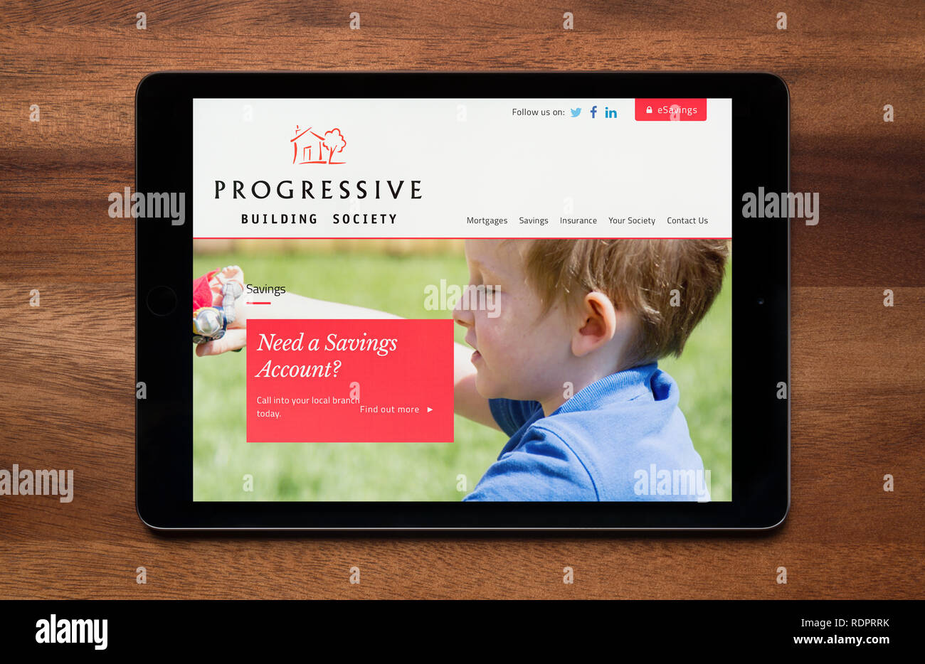 Il sito web di progressiva costruzione della società è visto su un tablet iPad, il quale è appoggiato su un tavolo di legno (solo uso editoriale). Foto Stock