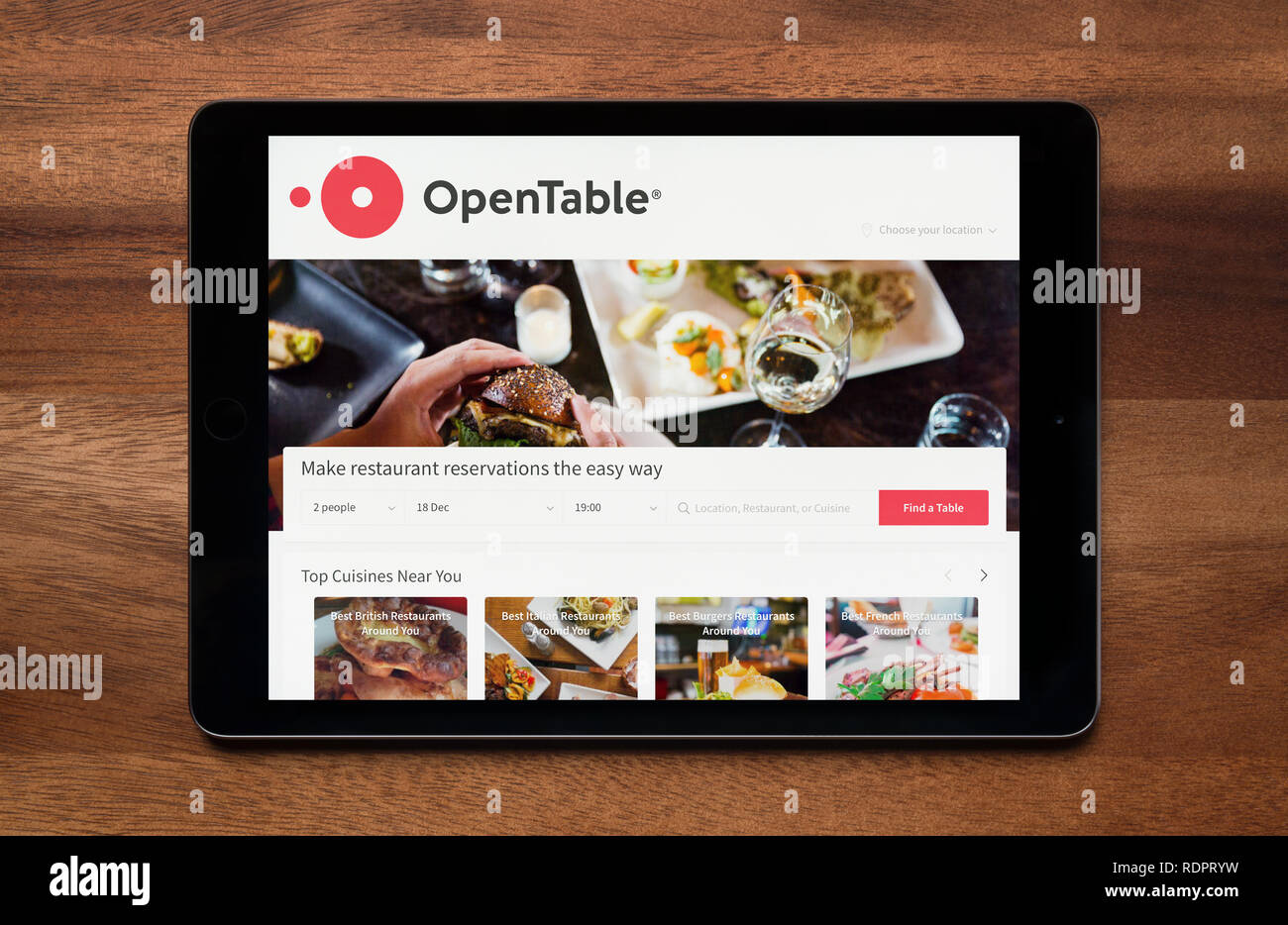 Il sito web di OpenTable è visto su un tablet iPad, il quale è appoggiato su un tavolo di legno (solo uso editoriale). Foto Stock