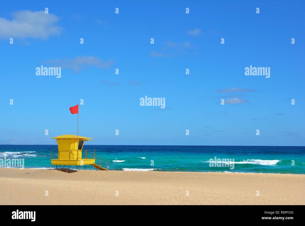 Bagnino giallo posto sulla spiaggia di Corralejo, Fuerteventura, Spagna. Golden Sands, nuvoloso cielo blu e oceano turchese. Foto Stock