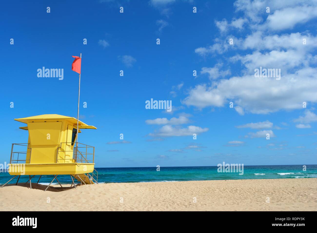 Bagnino giallo posto sulla spiaggia di Corralejo, Fuerteventura, Spagna. Golden Sands, nuvoloso cielo blu e oceano turchese. Foto Stock