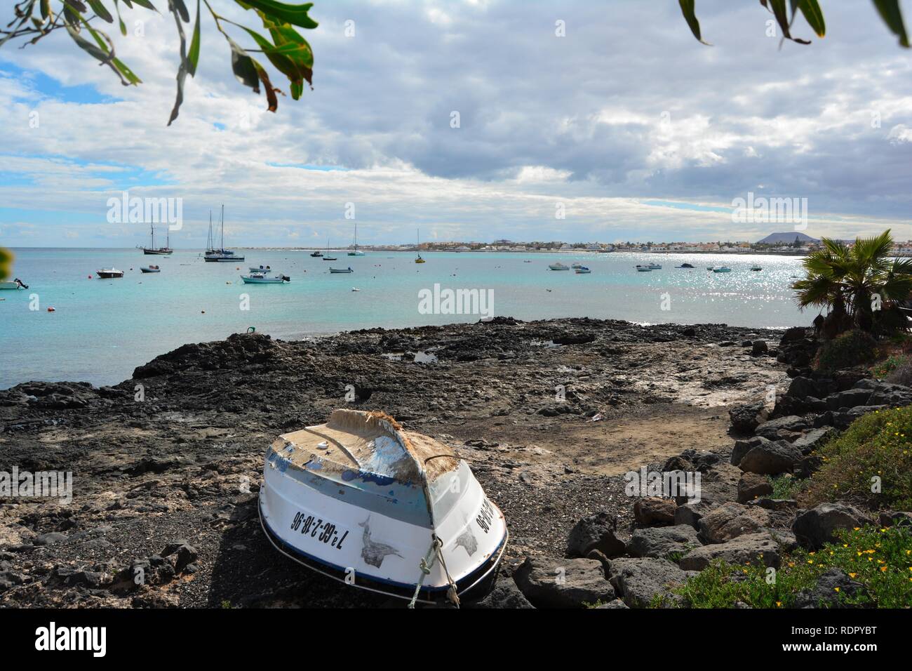 Vecchia barca abbandonata sulla costa rocciosa di Corralejo. Oceano turchese e scenic sky in background. Fuerteventura, Spagna. Foto Stock